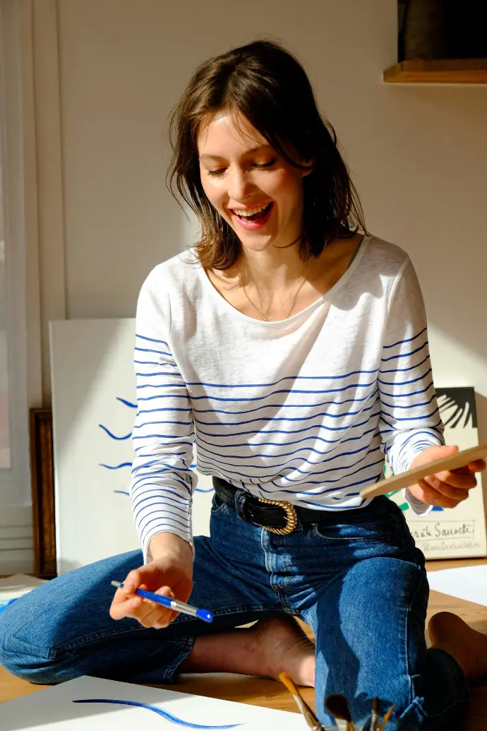 woman in white and black striped long sleeve shirt and blue denim jeans sitting on bed